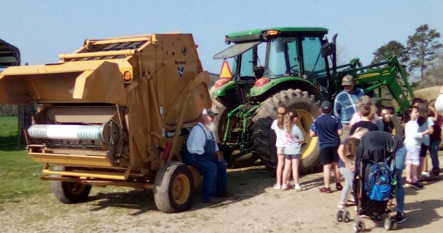 Group of 2nd graders looking at a tractor and hay baler at Ag Day 22. 